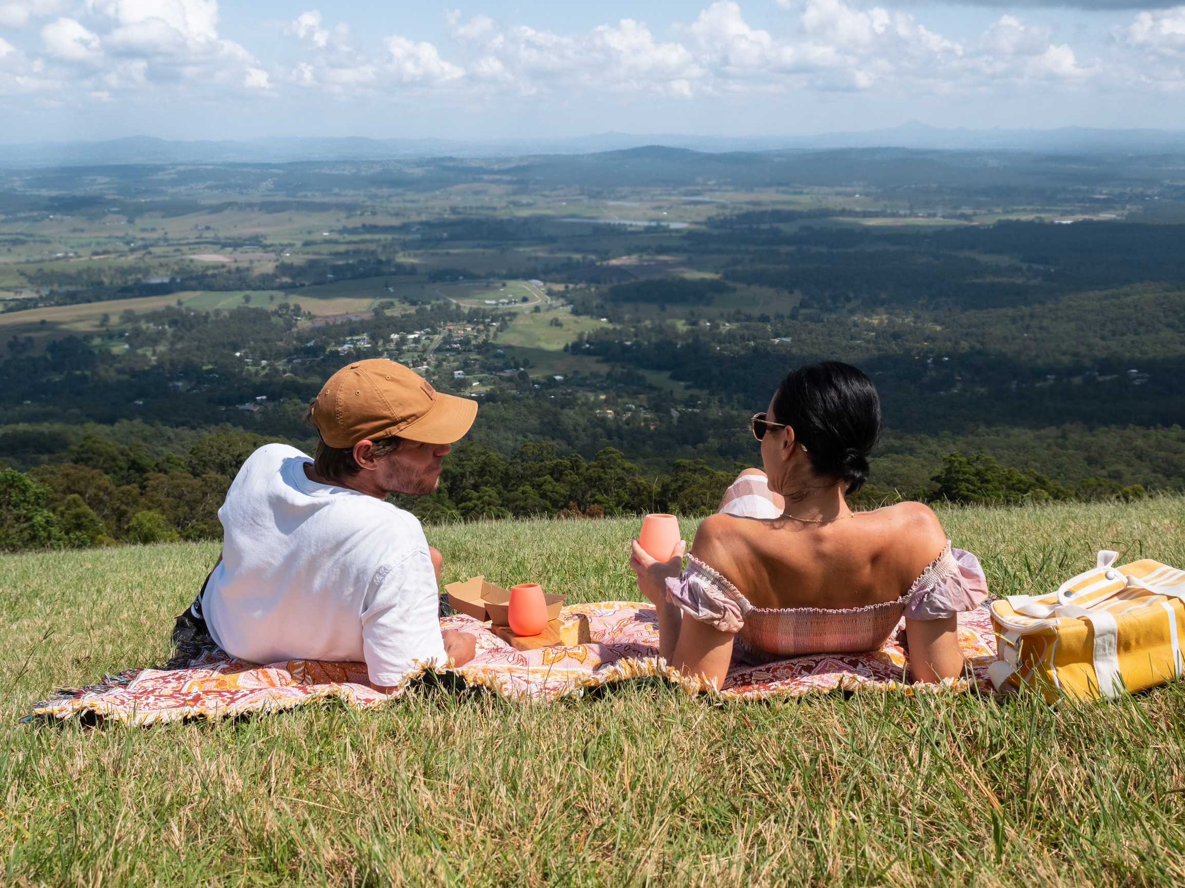 Couple enjoying a picnic on the grass, looking out over the valley Mt Tamborine Couple enjoying a picnic on the grass, looking out over the valley Mt Tamborine
