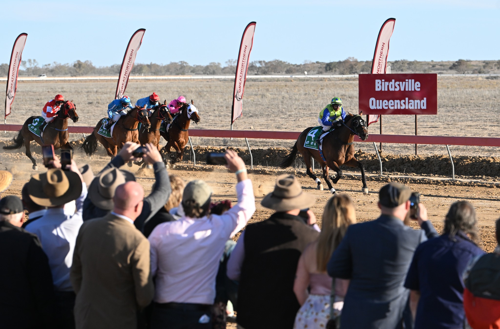 Crowds cheer on the horses on the home stretch at Birdsville Races