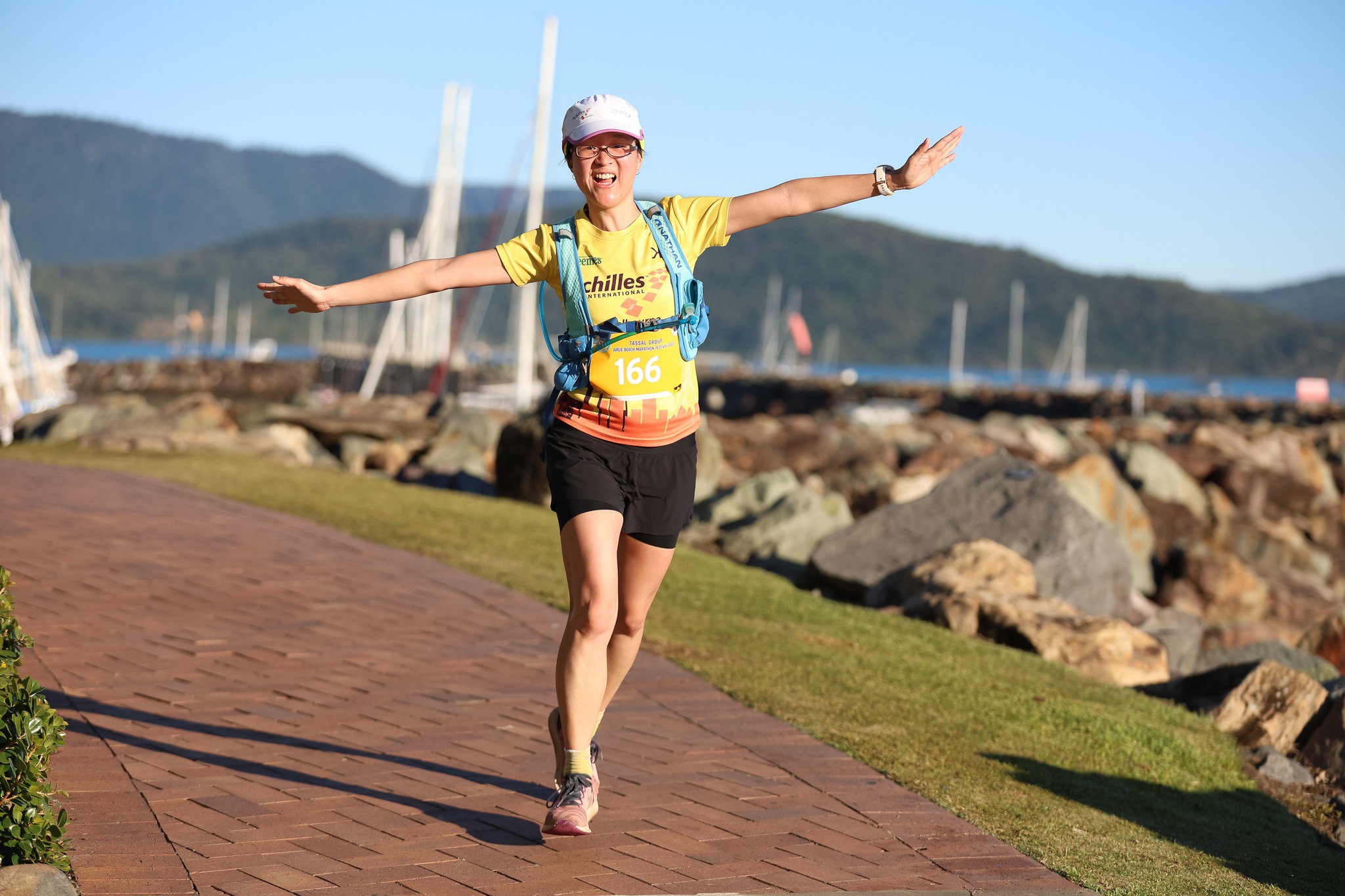 Female marathon competitor runs along a foreshore path near a marina