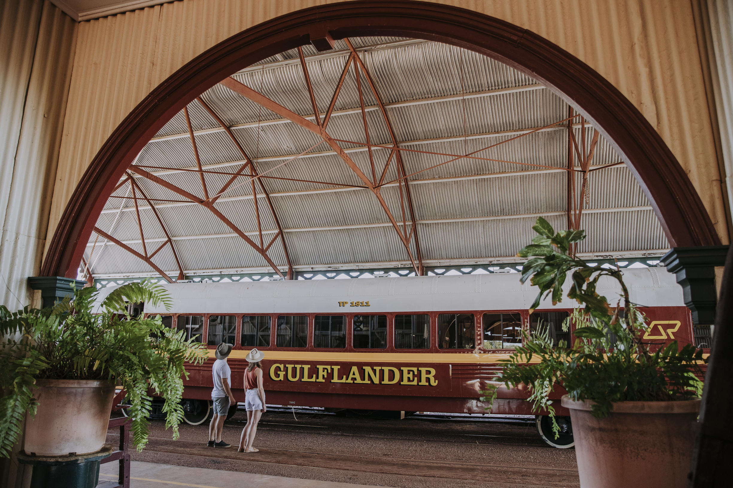 Two travellers are standing on the platform of Normanton Railway Station and admiring the heritage listed Gulflander train.