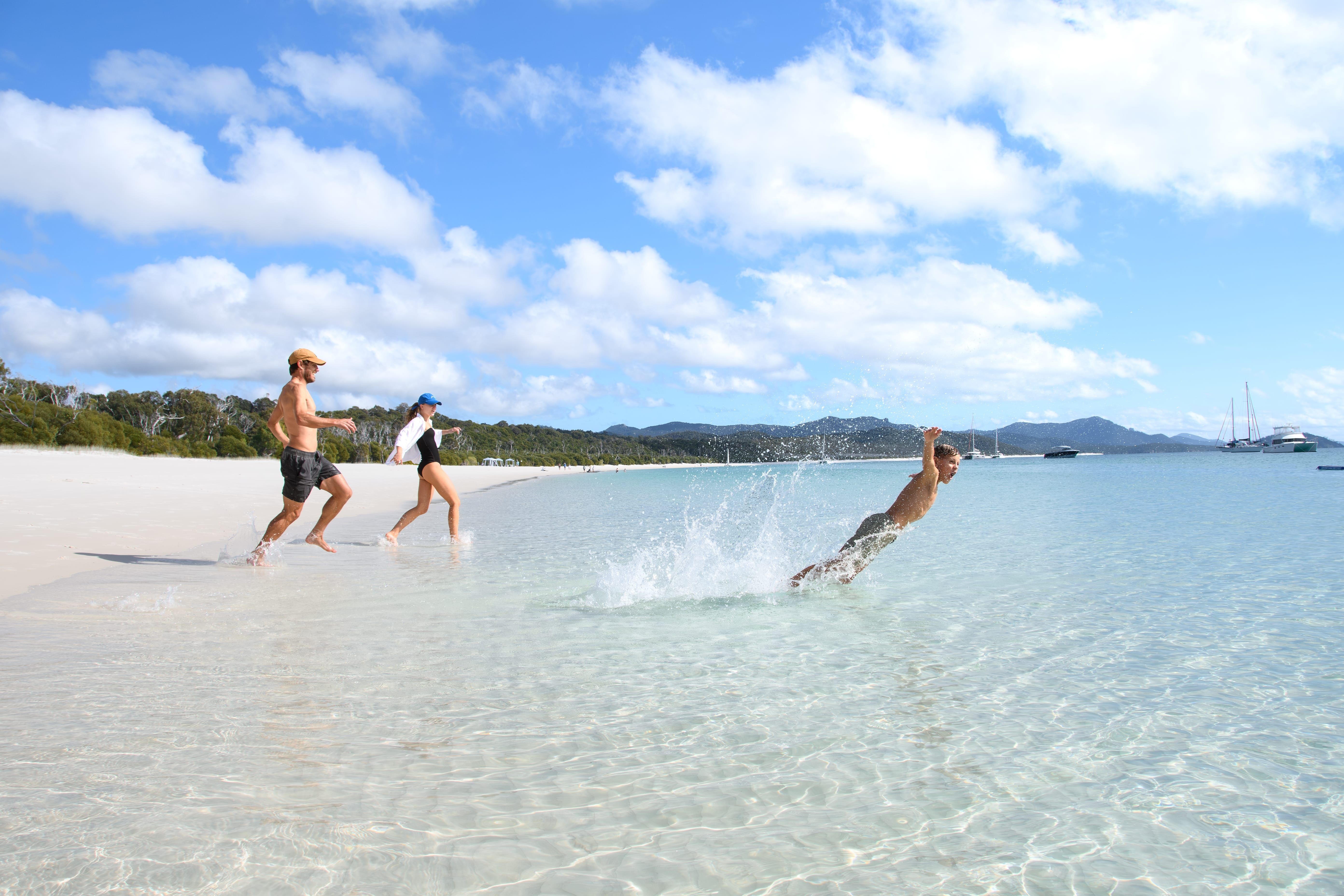 A family diving into the water at Whitehaven Beach